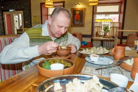 A man in a cafe eats a freshly prepared Caucasian dish. Stock Photos