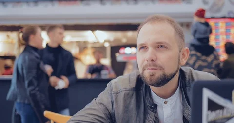 Man in a cafe with a laptop communicates with someone Vídeo Stock 95971045