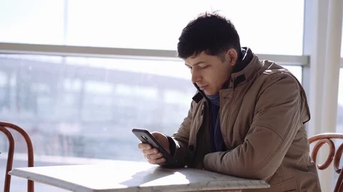Man in cafe thinking about something and holding smartphone in hands Stockbeeldmateriaal 105012689