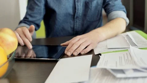 Man calculating checks on tablet while sitting by the table Vídeo Stock 70377504