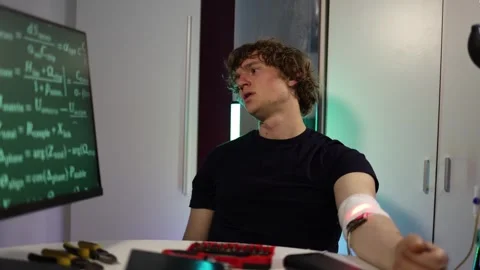 Man calibrates glowing implant while checking biometric data in lab Stock Footage 324443479