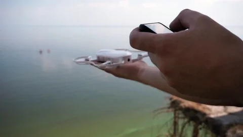 Man calibrating Drone using Smartphone by the sea Stock Footage 111279111