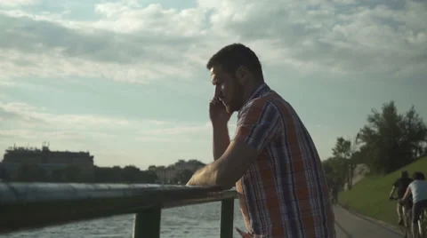 Man calling cell phone by the river near sunset. Vídeos de archivo 65930459