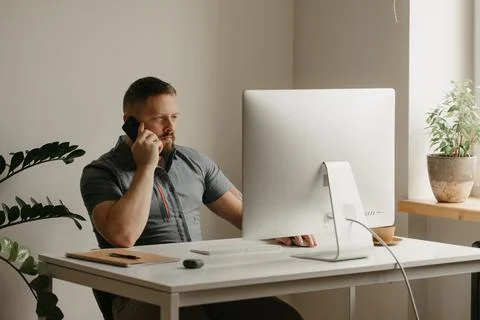 A man is calling during working remotely on a desktop computer at home Stock Photos