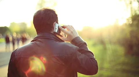 Man calling on mobile Phone at Sunset in park. View from the back. Stock-Footage 49751502