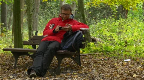 Man Calling on the Phone Sitting in a Park Beautiful Autumn Park Stock Footage 68686129