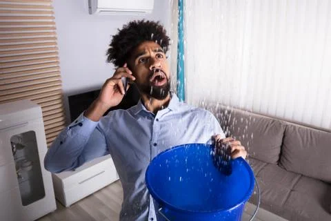 Man Calling Plumber While Leakage Water Falling Into Bucket Stock Photos