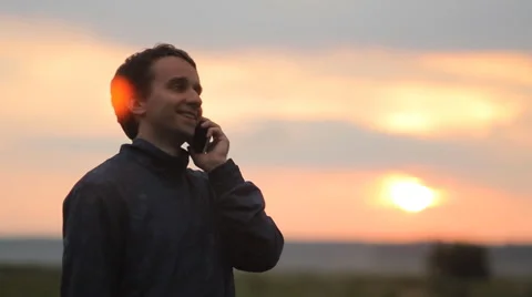 Man calling on the smart phone. Beautiful sunset on the background Stock Footage 64600268
