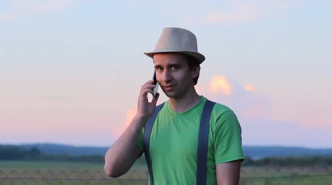 The man calls by phone. Against the backdrop of a beautiful sunset sky Stock Footage 64777032