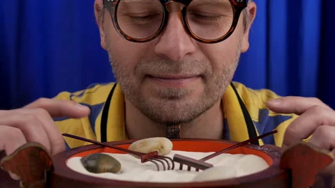 Man calms down using japanese mini rock garden. Stock Footage 134286760