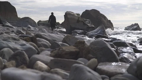 Man with camera along rocky beach at seaside Stock Footage 119152236