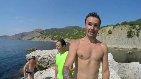 A man with a camera in his hand jumps into the water and shoots as he pops up Stock Footage 85950381