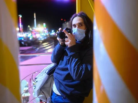 Man with a camera lying on the column of a fairground attraction at night Stock Photos
