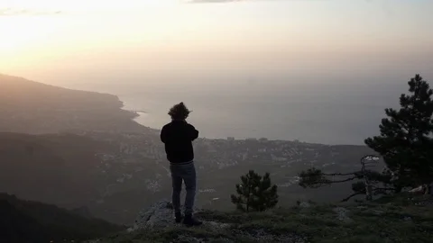 Man with the camera is on the mountain and takes pictures of the city Stock Footage 102697011