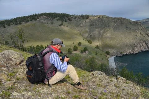 A man with a camera sitting on a hill Stock Photos