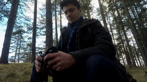 Man with camera sitting in woods 库存影片 86736453