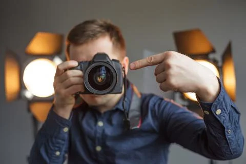 Man with a camera in the studio on the background lighting He points in lens  Stockfoto's