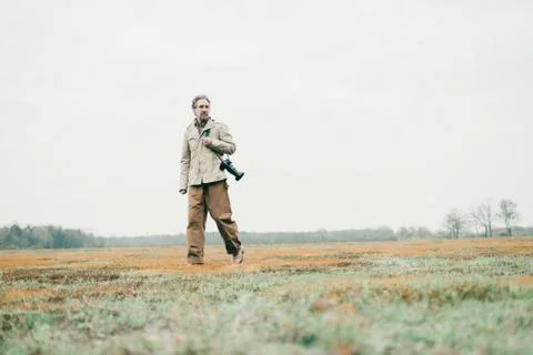 Man with camera walking over grassy land. Foto stock