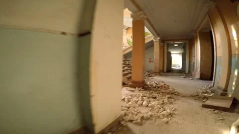 A man with a camera walks around an abandoned house, debris scattered on the Stock Footage 160909564