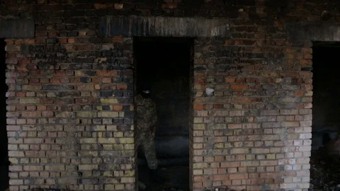 A man in camouflage and a black mask on an old abandoned building 스톡 동영상 73642425