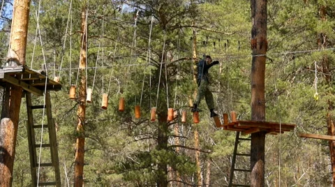 Man in camouflage trains move through suspended logs Stock Footage 49935239