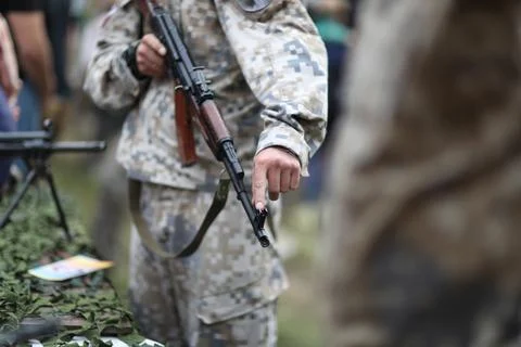 A man in camouflage uniforms explains the design of small arms Stock Photos