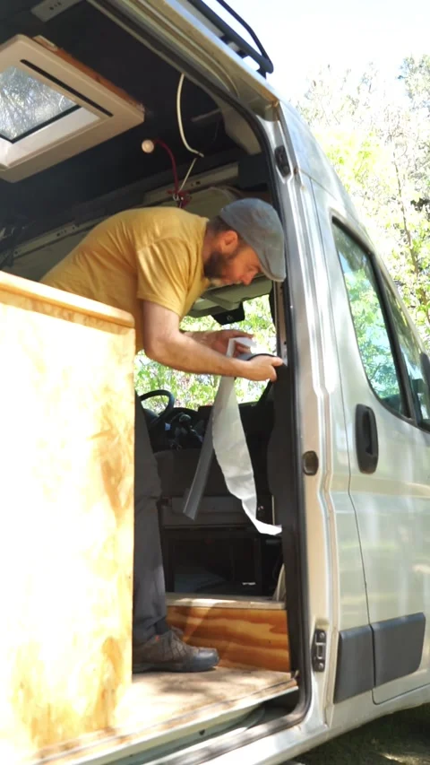 Man campering a camper van putting thermal insulation inside Stock Footage 274070713