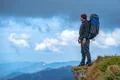 The man with a camping backpack standing on the cliff Photo
