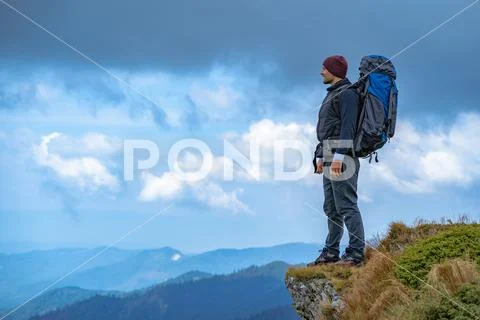 The man with a camping backpack standing on the cliff Stock Photos