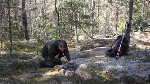 Man Camping in Forest, Building a Fire from Stones 库存影片 333403318