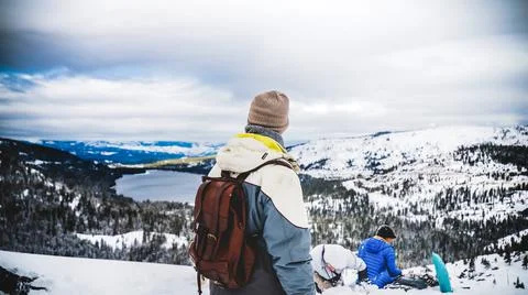 A man camping on a mountain looking at snow. Stock Photos