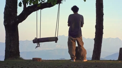 Man camping work outdoor and relax sit on wooden swing see layer of mountain Stock Footage 273290248