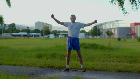 A man can be seen stretching outdoors while wearing athletic gear Stock-Footage 317514157