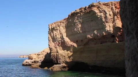 A man can just be seen walking high above on the clifftops of the Algarve coast. Stock Footage 65206451