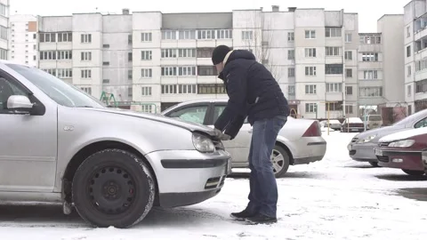 A man can not open the jammed hood in the car, winter, problem, snow Stock Footage 102819149