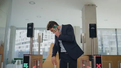 Man cannot enter office turnstile hurrying talking smartphone. Busy businessman Vidéo 259752352
