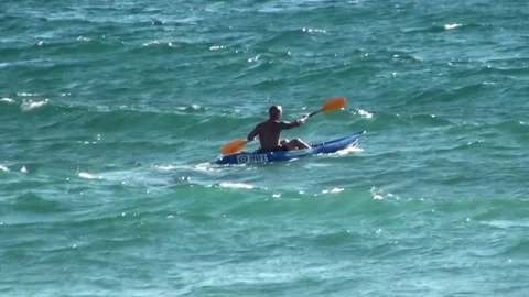 A man in a canoe swims over rough sea waves. Stock Footage 76709345