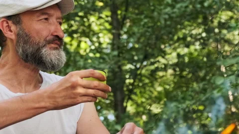 Man in a cap with a beard drinks hot coffee outdoors. Stock Footage 148338803