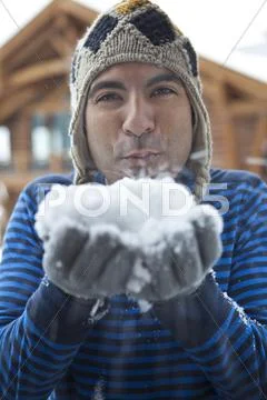 Man In Cap Blowing Snow