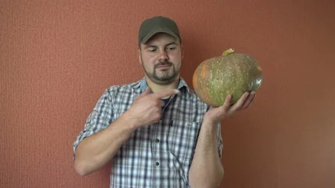 A man in a cap holding a pumpkin 4K Stock Footage 87787904