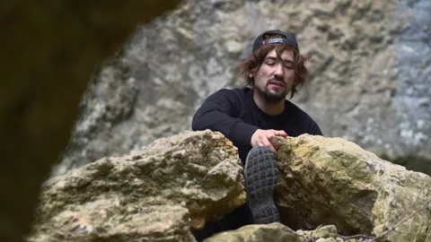Man with cap with leg trapped between two rocks saving her leg. Survival conc 스톡 동영상 153145114