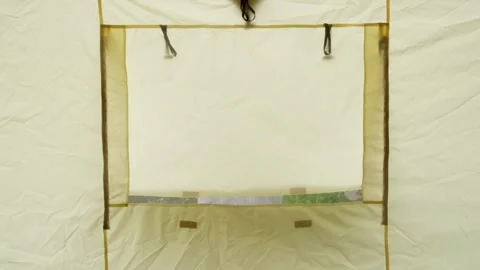 Man in a cap opens the window into the tent rolls up the window outside the tent Stock Footage 247048730