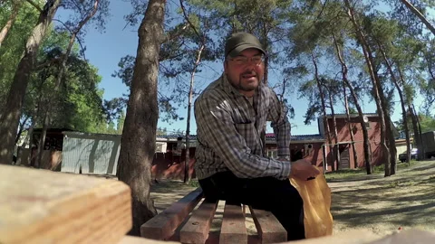 A man in a cap sits on a bench and talks Stock Footage 196214593