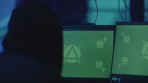 Man in the cap is sitting and working on stealing data at the computer as haker Stock Footage 122166717