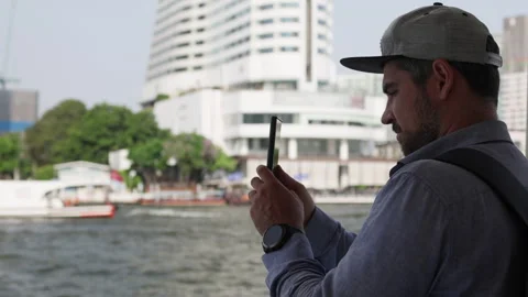 Man in cap taking pictures of river. Video stock 305773688