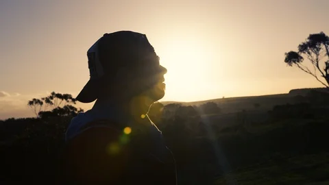 Man with cap walking down a country track at sunrise. Stock Footage 87857068