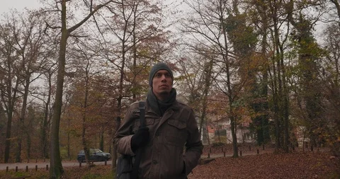 A man with a cap walking in the forest park in autumn Stock Footage 98111058
