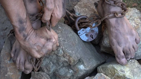 Man in captivity. The hands and feet of a slave are tied with iron chains. Vídeos de archivo 121697533