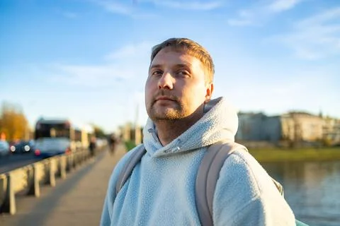 A man is captured in a contemplative pose, gazing upward in an urban riverside e Stock Photos