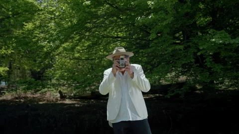 Man captures nature with analog camera in beautiful green park setting Stock Footage 321374700
